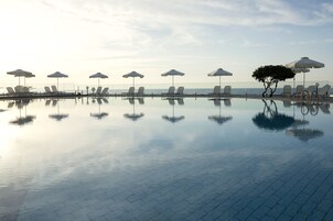 Una piscina al aire libre, sombrillas, sillones reclinables de piscina