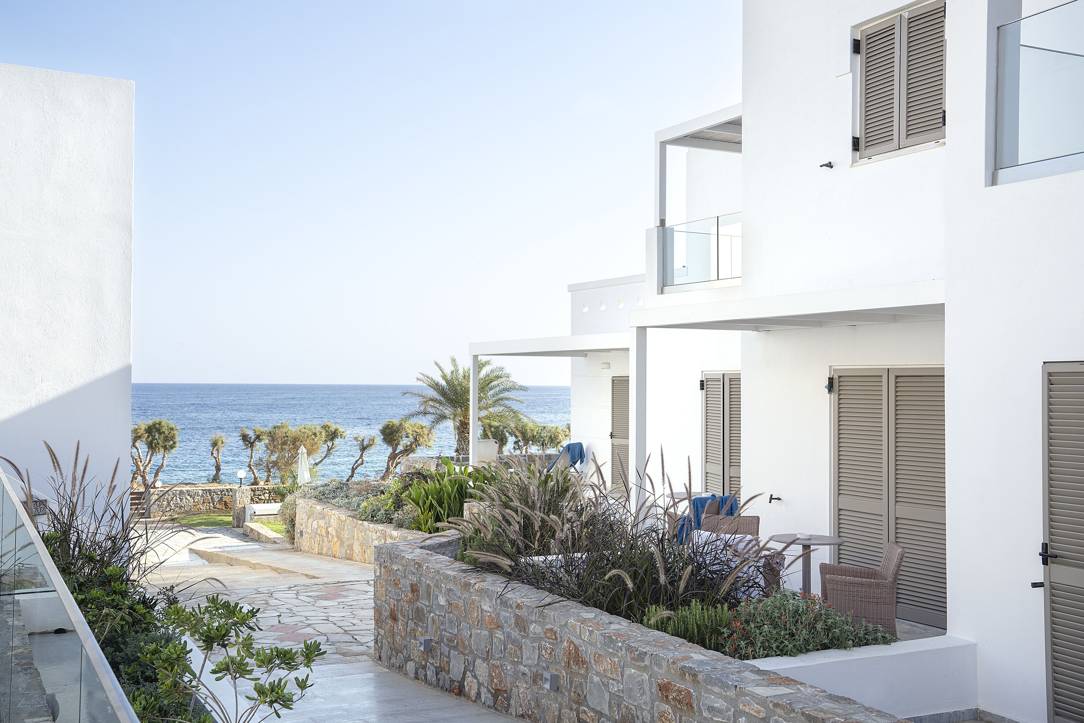 A modern building with a stone pathway leading to a balcony overlooking the sea.