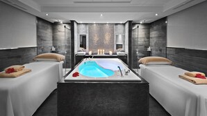 Een moderne spa-ruimte met een vrijstaand bad in het midden, twee bedden en een grote spiegel.