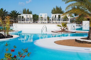 A resort pool area with multiple pools, lounge chairs, and cabanas.