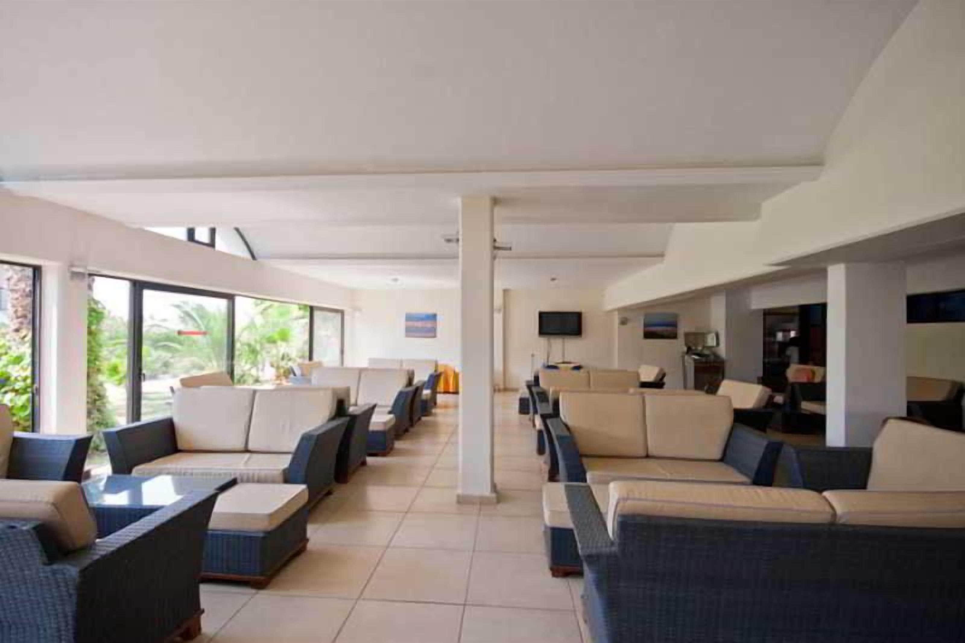 A hotel lobby with rows of seating, a television, and a view of the outdoors.