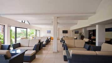 A hotel lobby with rows of seating, a television, and a view of the outdoors.