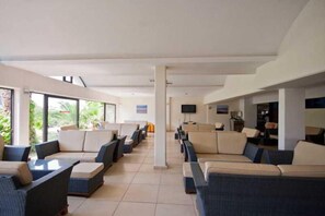 A hotel lobby with rows of seating, a television, and a view of the outdoors. - Tigaki Beach (Kos)