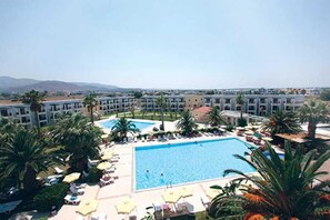 A hotel with multiple swimming pools, palm trees, and sun loungers. - Tigaki Beach (Kos)