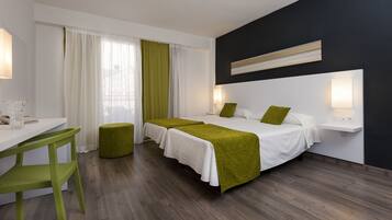 Una habitació d'hotel amb dos llits, un escriptori, una cadira i una taula de nit amb làmpades.