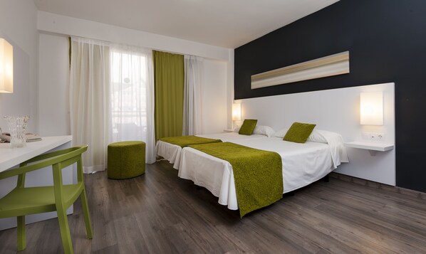 A hotel room with two beds, a desk, a chair, and a bedside table with lamps. - Kn Aparthotel Columbus (Arona)