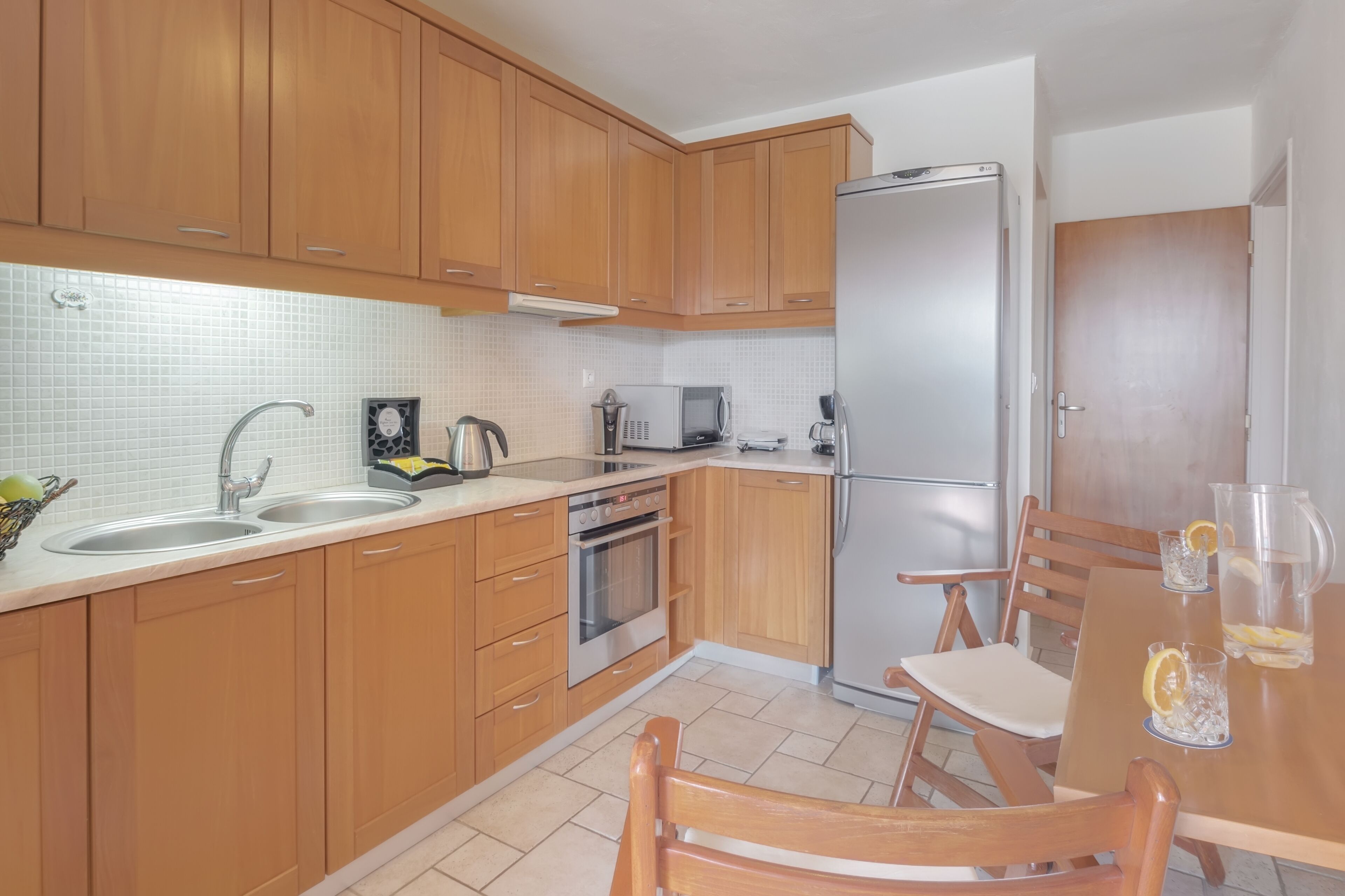 A modern kitchen with wooden cabinets, stainless steel appliances, and a dining area with a table and chairs.