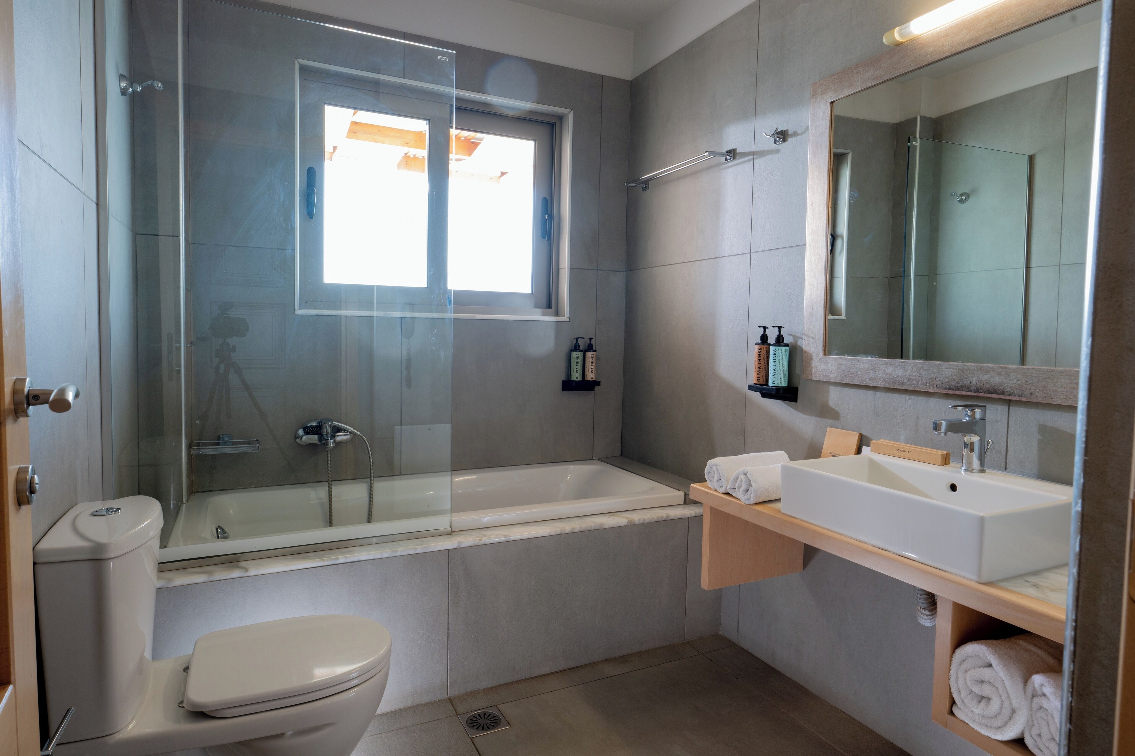 Une salle de bain moderne dotée d’une douche à parois de verre, d’une baignoire blanche, de toilettes et d’un meuble-lavabo avec un miroir et un évier.