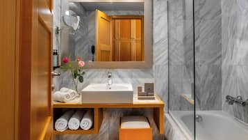 A modern bathroom with a wooden vanity, a large mirror, a white sink, and a glass-enclosed shower.