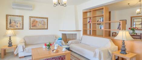 A living room with a sofa, a coffee table, a fireplace, and a bookshelf.
