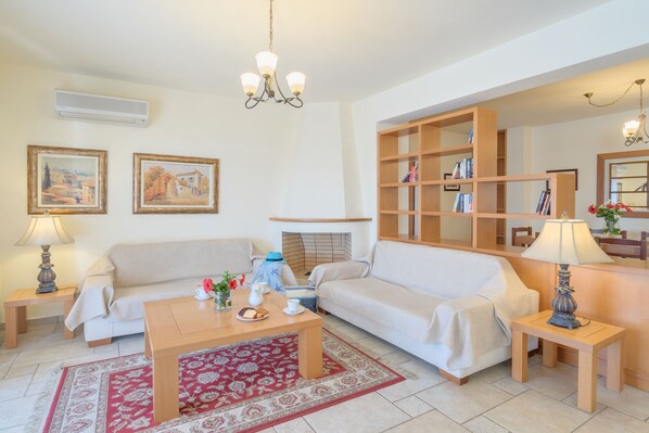 A living room with a sofa, a coffee table, a fireplace, and a bookshelf.
