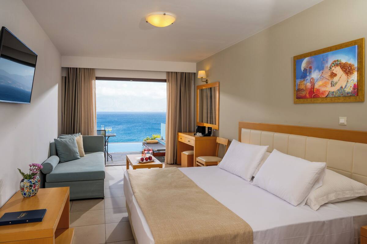 A hotel room with a bed, a sofa, a desk, and a TV.
