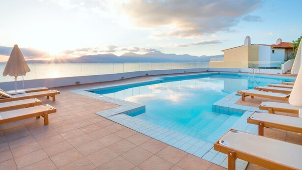 Une piscine avec des chaises longues et une vue sur la mer et les montagnes.
