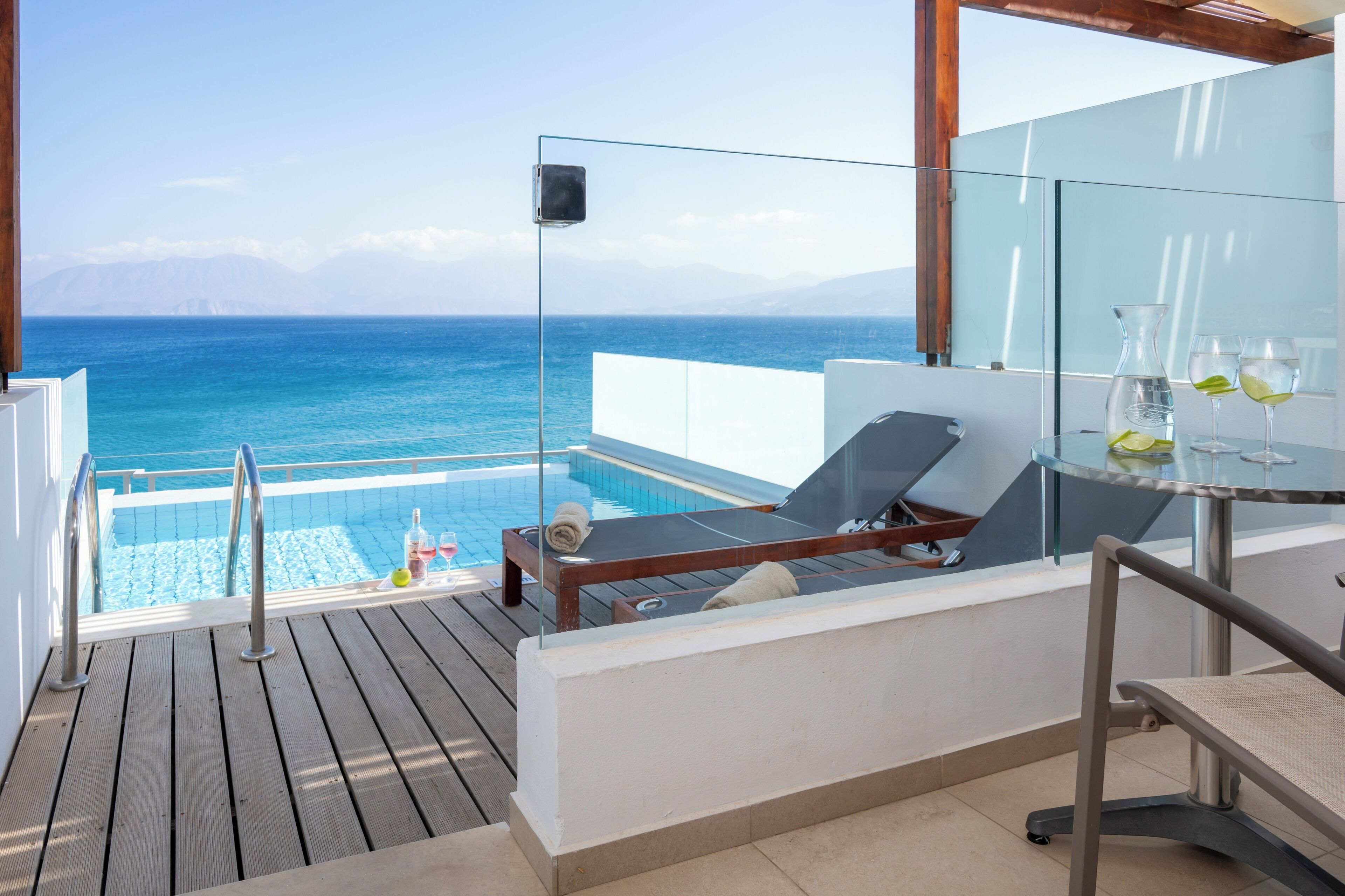 Balcón con barandilla de vidrio con vistas a una piscina y al mar.