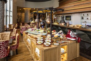 A restaurant with a wooden bar area, various dishes displayed, and a seating area with upholstered chairs.