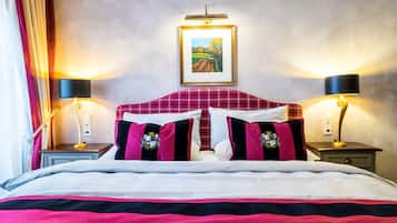 A hotel room with a bed, two bedside tables, a nightstand, a framed picture on the wall, and a window with curtains.