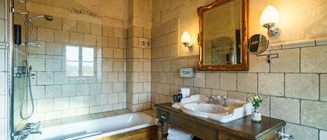 Un baño con bañera, lavabo, espejo y ducha.