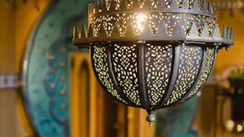 Un lampadario con lavorazioni metalliche elaborate e due vasi in ottone su una superficie piastrellata.