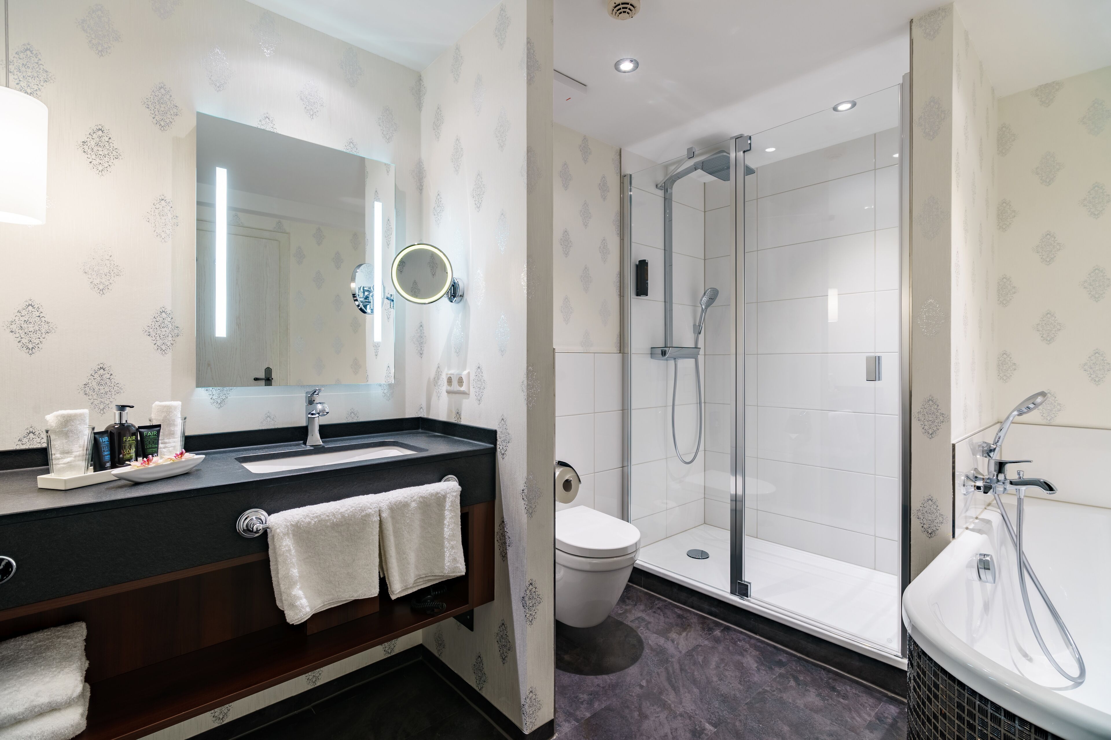 A modern bathroom with a large mirror, a sink, a toilet, and a shower area.
