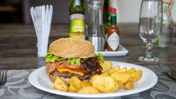 Un plato con una hamburguesa y papas fritas, una botella de kétchup y un vaso de agua sobre una mesa.
