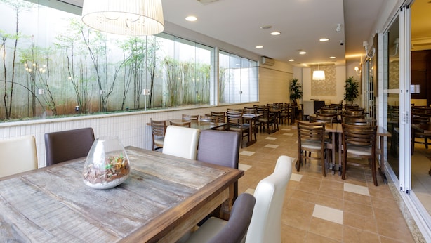 A spacious dining area with large windows, wooden tables, and comfortable seating. - Interclass Florianópolis (Florianópolis)