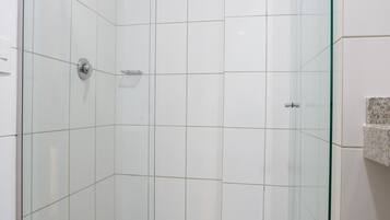 A glass-enclosed shower stall with white tiles and a metal showerhead.