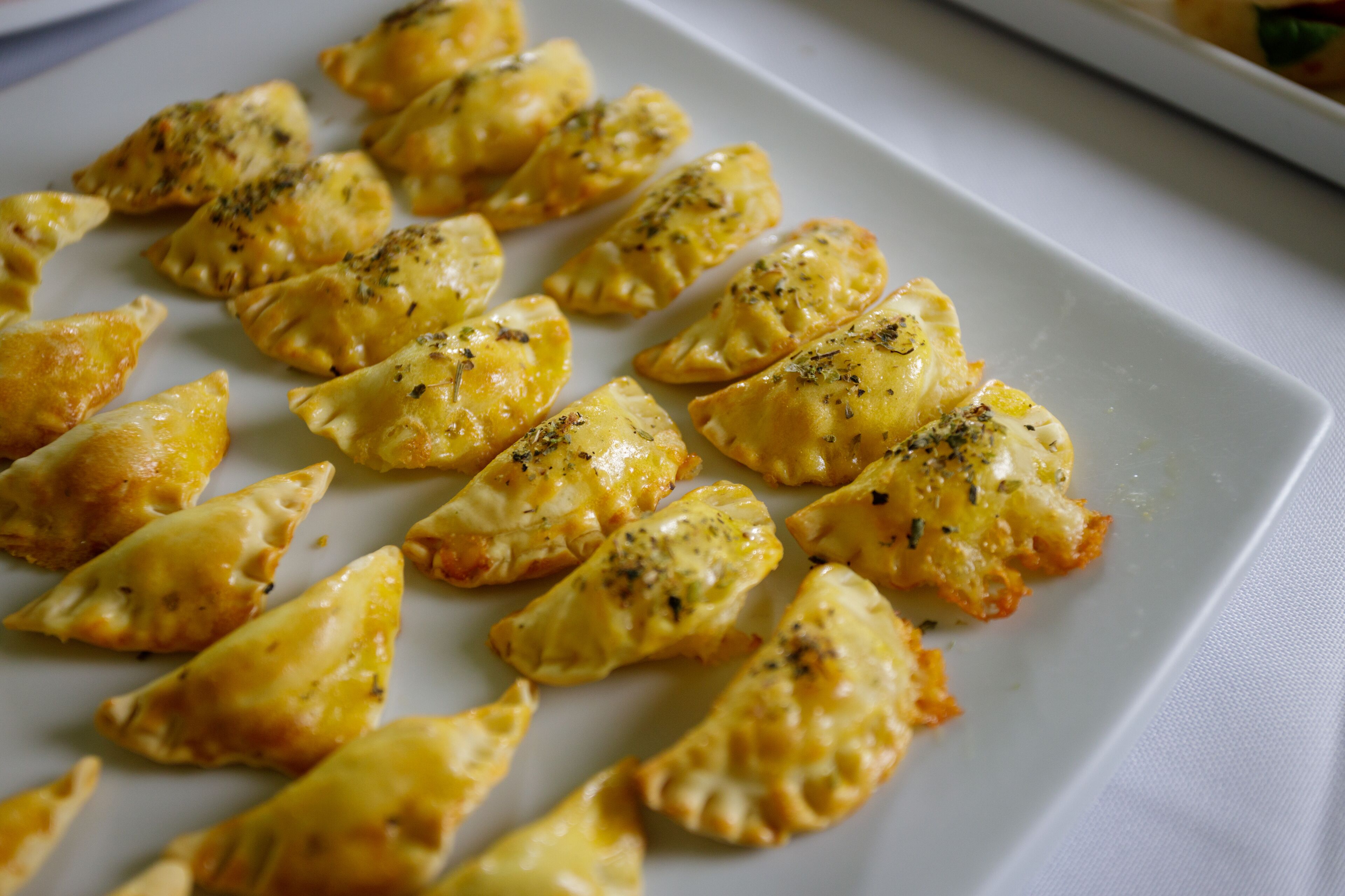A white plate with golden-brown pastries sprinkled with herbs.