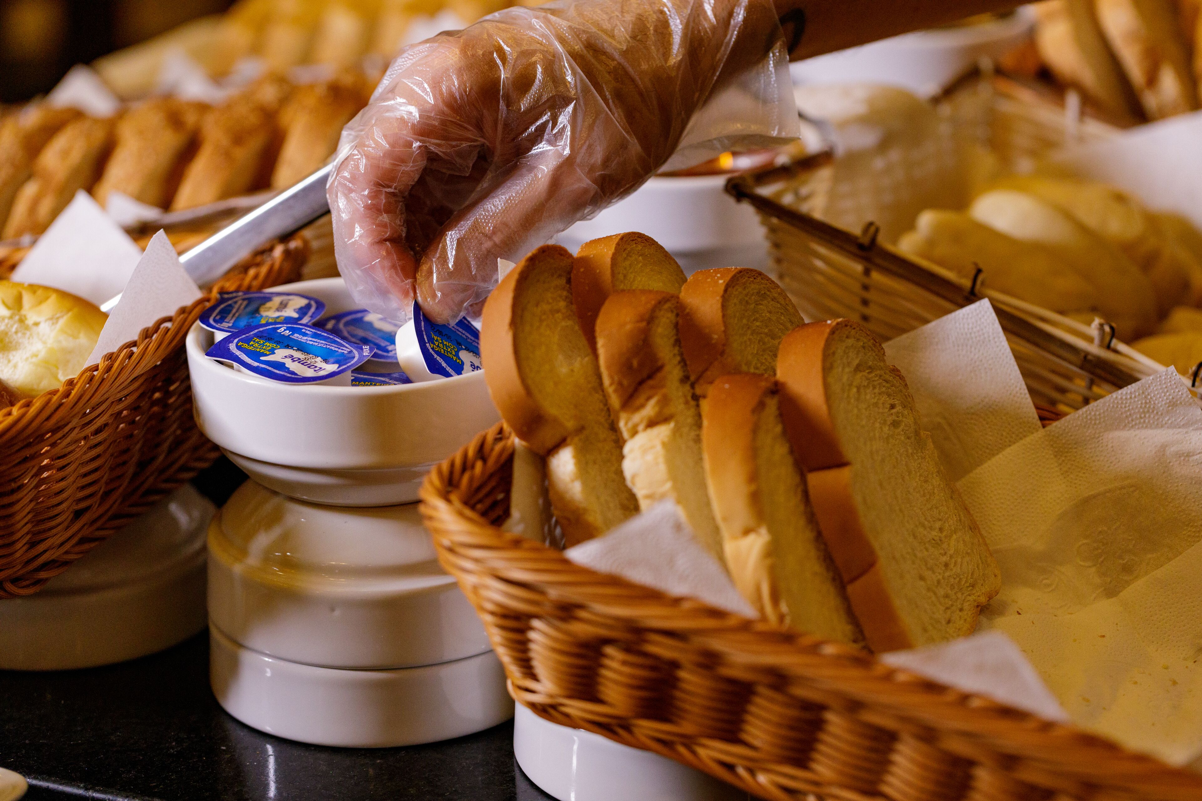 A buffet setup with baskets of bread and a bowl of dip.