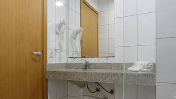 A bathroom with a wooden door, a sink with a mirror above it, and a toilet.