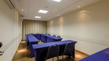 Una sala conferenze con un lungo tavolo e sedie, un soffitto con illuminazione a incasso e una finestra con tende.
