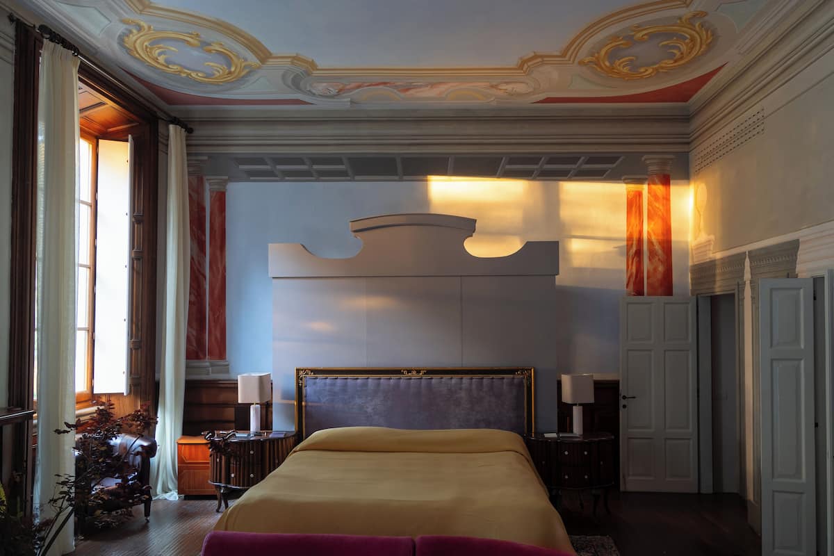 A spacious bedroom with a large bed, a nightstand, a chair, and a desk.