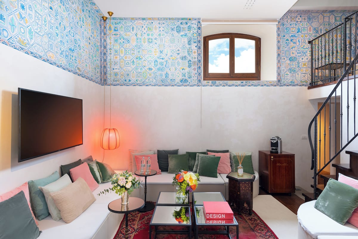 A living room with a patterned ceiling, a sofa with cushions, a coffee table, a TV, and a staircase.