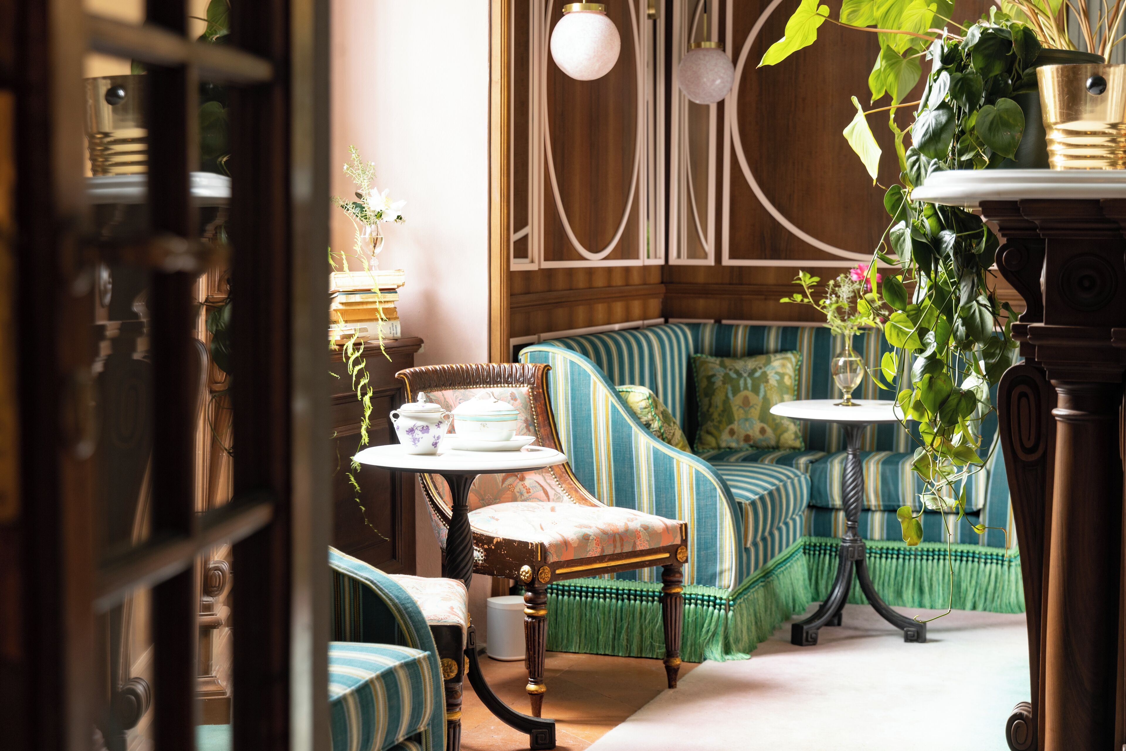 A cozy seating area with striped sofas, a small table with a teapot, and a potted plant.