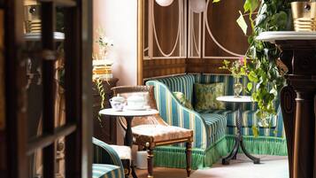 A cozy seating area with striped sofas, a small table with a teapot, and a potted plant.