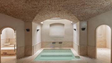 Un cuarto de spa con una bañera grande, arcos y un techo de ladrillo.