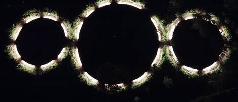 Ein dunkler Himmel mit drei beleuchteten Ringen, die an die Olympischen Ringe erinnern.
