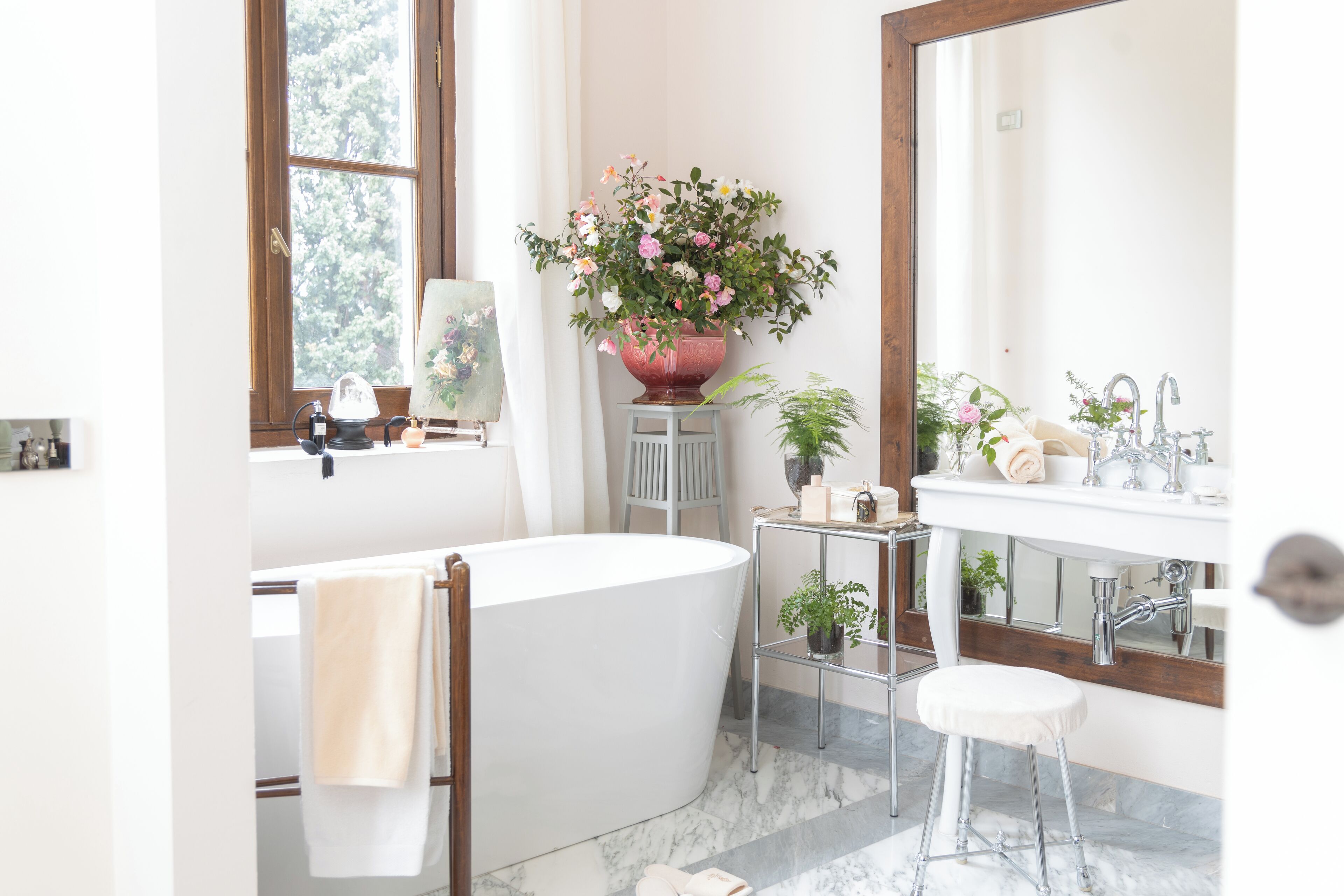 Un baño moderno con una bañera independiente, un tocador con espejo y una planta en maceta.