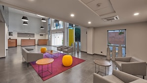 Un vestíbulo espacioso con muebles modernos, una zona de cocina y ventanas amplias que ofrecen vistas al exterior.