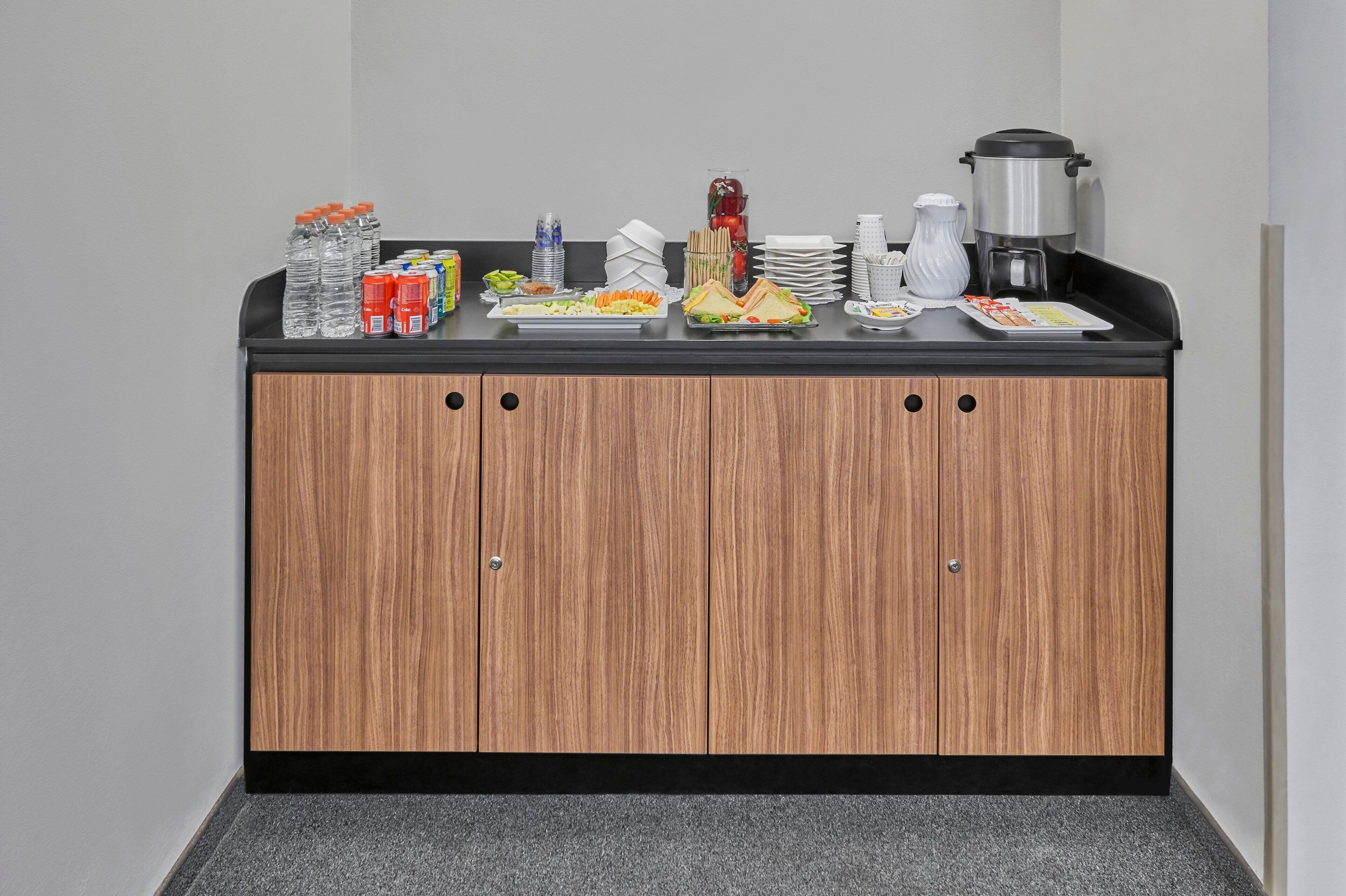 A hotel buffet counter with a variety of food items, beverages, and a coffee maker.