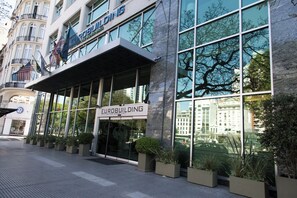 Un edificio moderno con una amplia fachada de vidrio, un cartel que dice 'EUROBUILDING' y el reflejo de árboles en las ventanas.