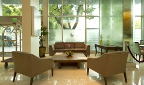 Un hall d’entrée avec un canapé, deux fauteuils, une table basse et une plante en pot.