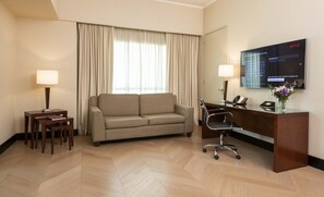 A hotel room with a sofa, a desk with a computer, a chair, and a TV mounted on the wall. - Eurobuilding Hotel Boutique Buenos Aires (Buenos Aires)