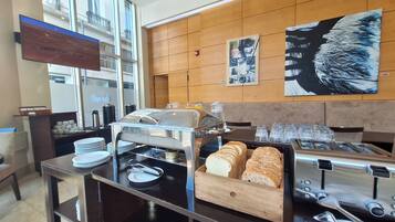 Montaje de bufé con diversos alimentos, incluyendo panadería y pastelería, además de una selección de bebidas.