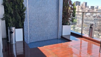 Una terraza en la azotea con un muro de azulejos azules, una cubierta de madera y vistas a la ciudad.