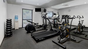 Un gimnasio moderno con máquinas de cardio, mancuernas y un dispensador de agua.