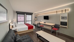 Una habitación de hotel moderna con cama, sofá, escritorio y zona de estar.