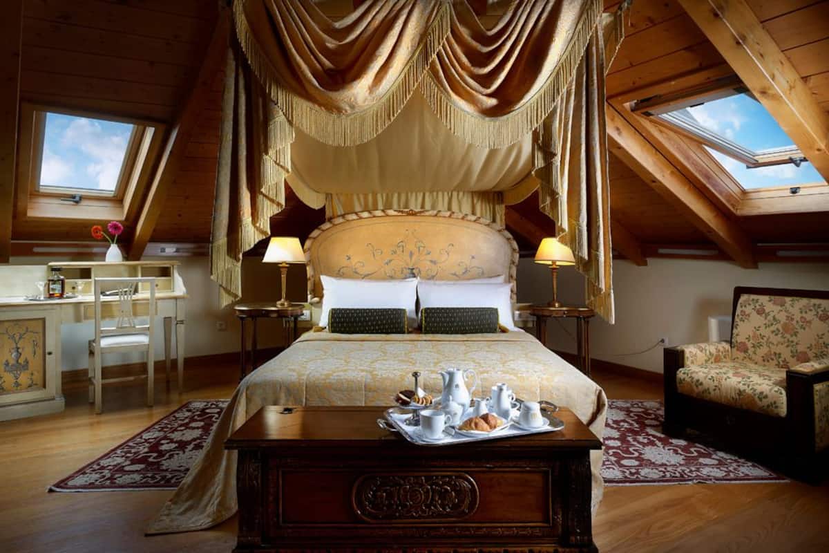 Ein Schlafzimmer mit einem großen Bett, zwei Nachttischen, einem Schreibtisch, einem Stuhl und einem Fenster.