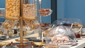 A buffet setup with various food items in clear containers and a central display with a golden design. - Grande Bretagne (Nafplio)