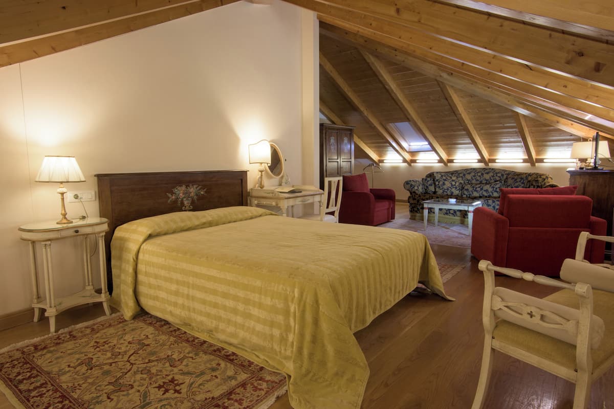 Ein Schlafzimmer mit Bett, Nachttisch, Lampe, Kommode und einem roten Sessel.