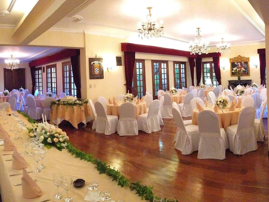 Un salón de banquetes con largas mesas dispuestas para un evento formal, con candelabros y centros de mesa florales.